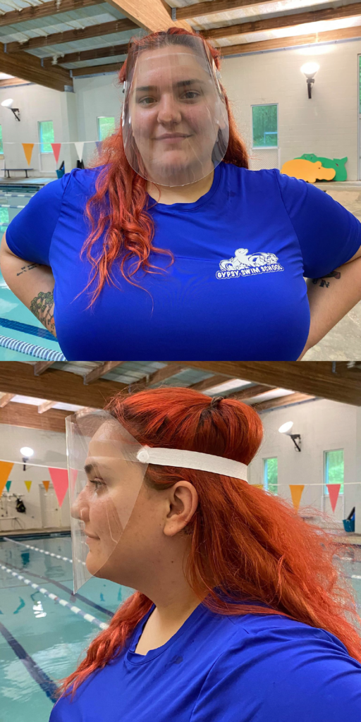 A swim instructor demos the face shields used by the swim instructors. A long plastic cover starts above her forehead and goes down below her chin, covering her whole face.