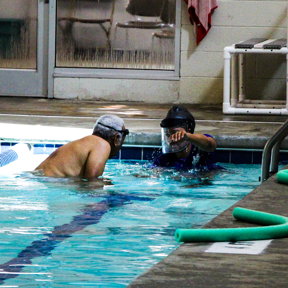 Instructor demonstrating a swimming stroke to student