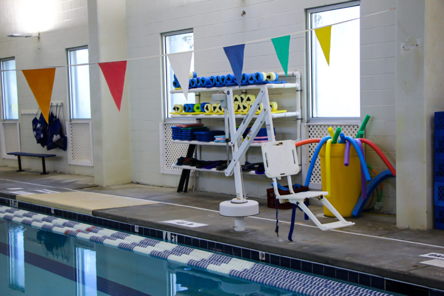 Our chair lift is in the foreground, next to the pool edge, and some of our swim lesson equipment is in the back, including kick boards and pool noodles.